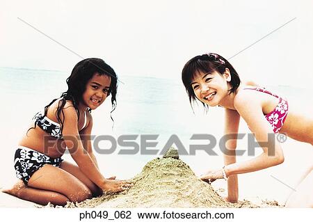 Young woman and Hawaiian girl building sandcastle on beach View Large Photo Image Stock Image - Young woman and Hawaiian girl building sandcastle on beach . Fotosearch