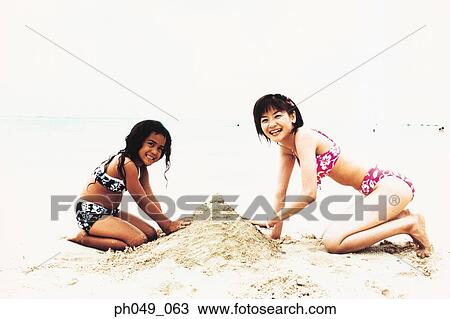 Young woman and Hawaiian girl building sandcastle on beach View Large Photo Image Stock Image - Young woman and Hawaiian girl building sandcastle on beach . Fotosearch