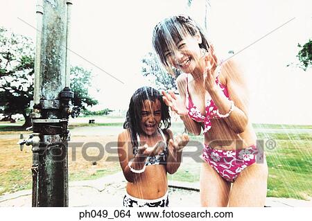 Young woman and Hawaiian girl under running water View Large Photo Image Picture - Young woman and Hawaiian girl under running water. Fotosearch