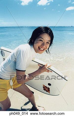 Young woman at a beach, holding paddleboard View Large Photo Image Picture - Young woman at a beach, holding paddleboard . Fotosearch