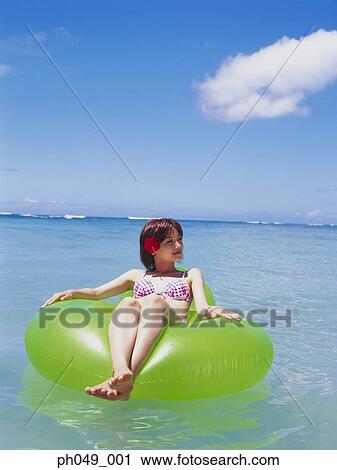 Young woman floating in water on inflatable ring  View Large Photo Image Stock Image - Young woman floating in water on inflatable ring . Fotosearch