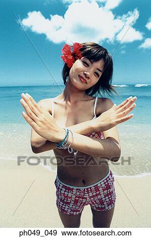Stock Photo - Young woman in bikini at a beach, arms crossed, portrait. Fotosearch