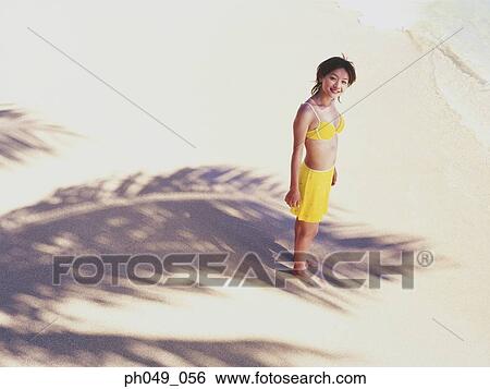Stock Photograph - Young woman in bikini at a beach, looking up. Fotosearch