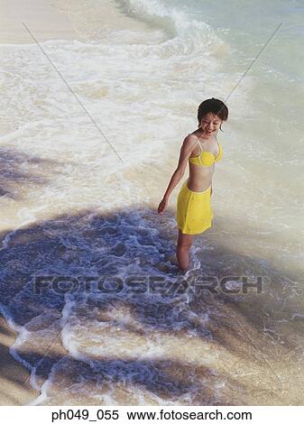 Stock Photography - Young woman in bikini at a beach, looking up. Fotosearch