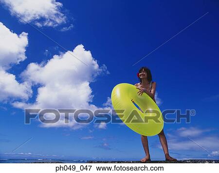 Young woman in bikini at a water breaker, holding yellow float View Large Photo Image Stock Photo - Young woman in bikini at a water breaker, holding yellow float. Fotosearch