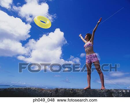 Young woman in bikini at a water breaker, throwing a yellow float View Large Photo Image Stock Photo - Young woman in bikini at a water breaker, throwing a yellow float. Fotosearch