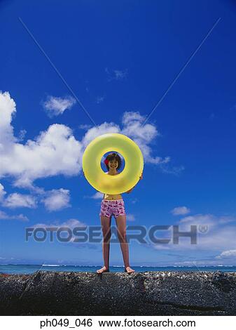 Young woman in bikini at a water breaker, holding yellow float View Large Photo Image Stock Photograph - Young woman in bikini at a water breaker, holding yellow float. Fotosearch