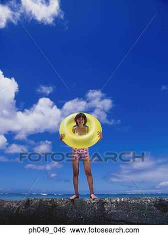 Young woman in bikini at a water breaker, holding yellow float View Large Photo Image Stock Photography - Young woman in bikini at a water breaker, holding yellow float. Fotosearch