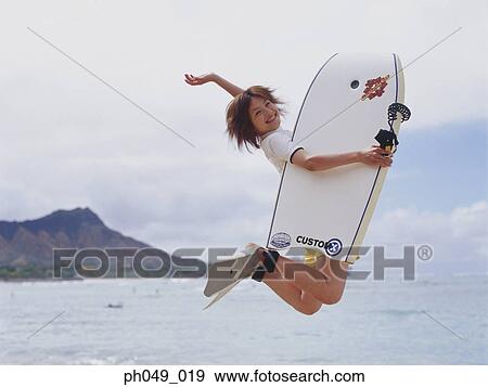 Young woman jumping in air, holding paddleboard View Large Photo Image Stock Photo - Young woman jumping in air, holding paddleboard. Fotosearch