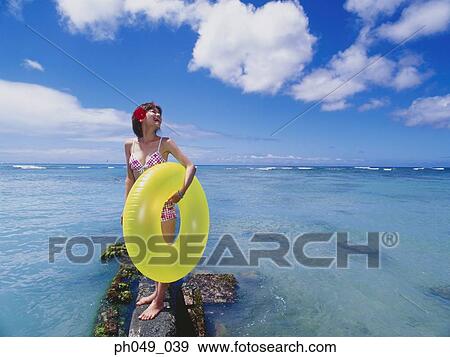 Young woman on stone holding yellow float View Large Photo Image Stock Photo - Young woman on stone holding yellow float. Fotosearch