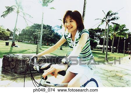 Young woman riding bicycle in the park View Large Photo Image Picture - Young woman riding bicycle in the park. Fotosearch