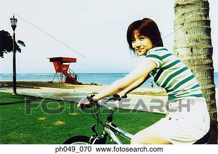 Young woman riding bicycle in the park View Large Photo Image Stock Image - Young woman riding bicycle in the park. Fotosearch
