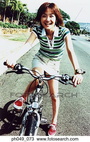 Stock Image - Young woman riding bicycle in the park. Fotosearch
