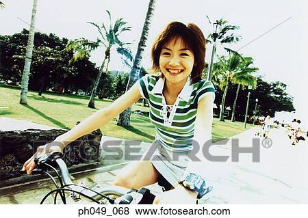Stock Photo - Young woman riding bicycle in the park. Fotosearch
