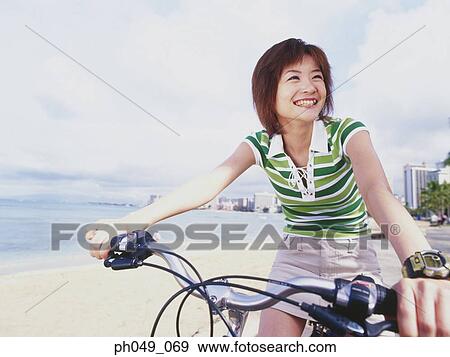 Stock Photo - Young woman riding bicycle in the park. Fotosearch