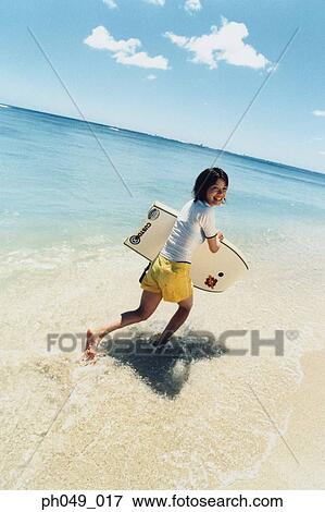 Young woman running at a beach with surfboard View Large Photo Image Stock Photo - Young woman running at a beach with surfboard . Fotosearch