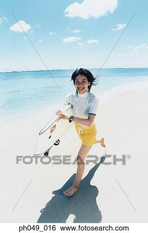 Young woman running at a beach with surfboard View Large Photo Image Stock Photograph - Young woman running at a beach with surfboard . Fotosearch