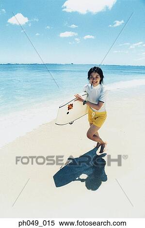 Young woman running at a beach with surfboard View Large Photo Image Stock Photography - Young woman running at a beach with surfboard . Fotosearch