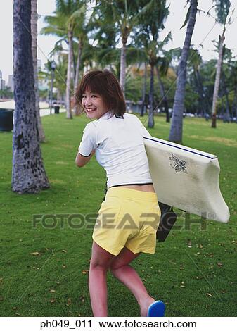 Young woman running on lawn with surfboard View Large Photo Image Stock Image - Young woman running on lawn with surfboard . Fotosearch