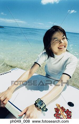 Young woman sitting on beach, holding a paddleboard View Large Photo Image Stock Photo - Young woman sitting on beach, holding a paddleboard . Fotosearch