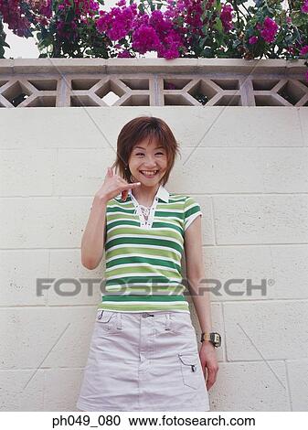 Young woman standing against wall, smiling View Large Photo Image Stock Image - Young woman standing against wall, smiling. Fotosearch