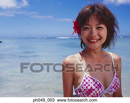Stock Image - Young woman wearing bikini, at a beach, smiling . Fotosearch