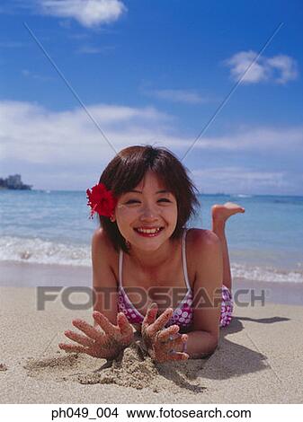 Picture - Young woman wearing bikini lying on beach, close-up . Fotosearch
