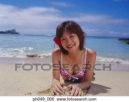 Stock Photography - Young woman wearing bikini lying on beach, close-up . Fotosearch
