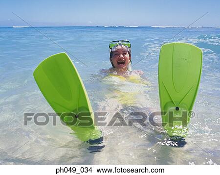 Young woman wearing snorkels and flippers, sitting in shallows View Large Photo Image Picture - Young woman wearing snorkels and flippers, sitting in shallows . Fotosearch