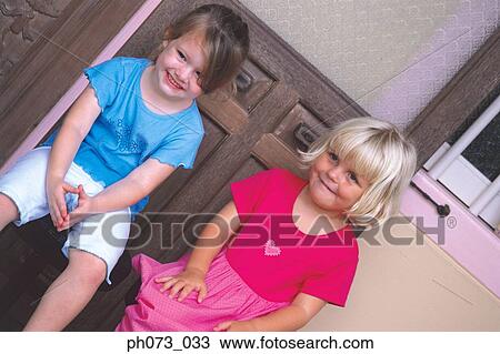 Stock Image - Two girls sitting beside each other. Fotosearch