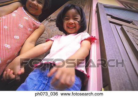 Two girls standing beside each other holding hands View Large Photo Image Stock Photograph - Two girls standing beside each other holding hands. Fotosearch