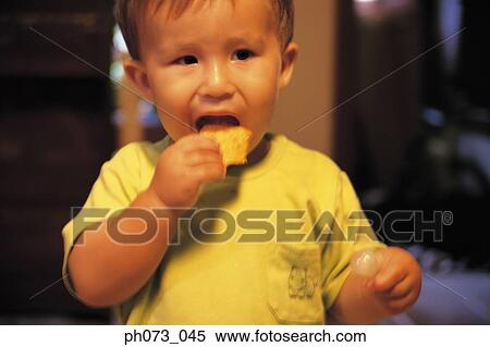 Stock Photography - Young boy eating cracker. Fotosearch