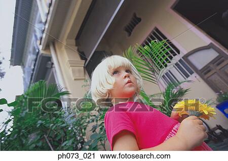 Stock Image - Young girl holding yellow flower. Fotosearch