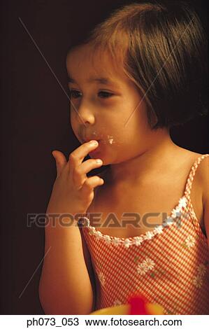 Stock Image - Young girl licking her fingers. Fotosearch
