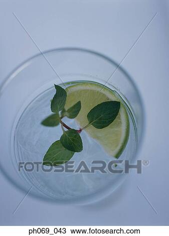 Stock Image - Glass of gin tonic and lemon slice and mint leaves, top view. Fotosearch