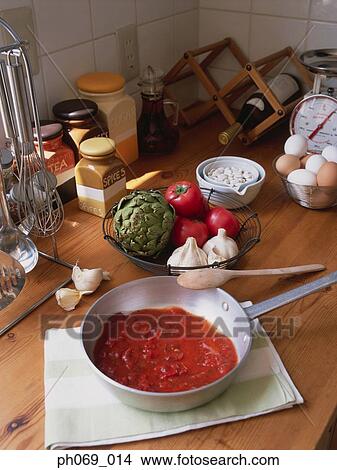 Picture - Pan of tomato sauce and ingredients on kitchen table. Fotosearch