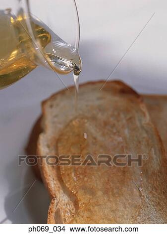 Picture - Pouring olive oil on toast. Fotosearch