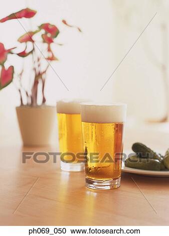 Two glasses of beer with foamy heads and a plate of pickles View Large Photo Image Stock Image - Two glasses of beer with foamy heads and a plate of pickles. Fotosearch