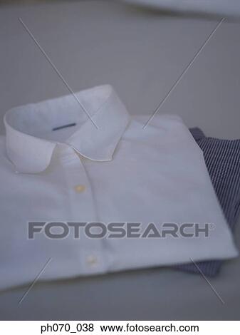 Stock Photo - Nicely folded white business shirt placed on bed. Fotosearch