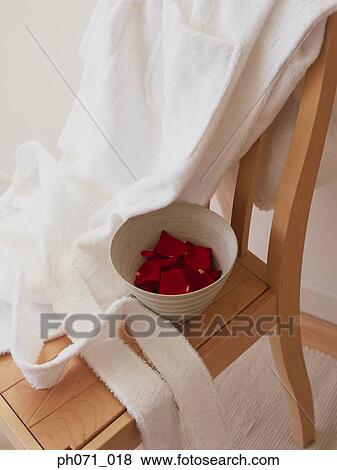 Stock Photo - Bowl of rose petals and bathrobe on chair. Fotosearch