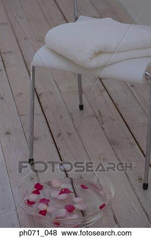 Stock Photo - Bowl of rose petals and folded white towel on chair. Fotosearch
