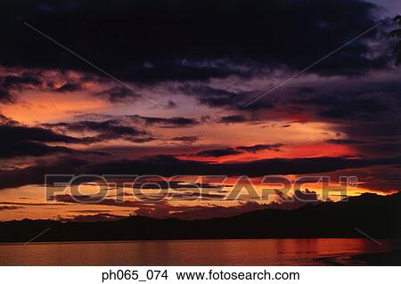 Sunset at sea, dark clouds in orange streaked sky View Large Photo Image Picture - Sunset at sea, dark clouds in orange streaked sky . Fotosearch