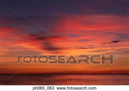 Sunset at sea, dark clouds in orange streaked sky View Large Photo Image Stock Image - Sunset at sea, dark clouds in orange streaked sky . Fotosearch