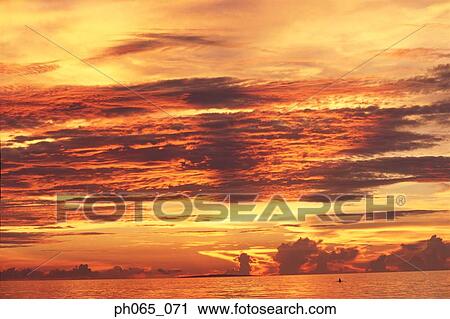Sunset at sea, dark clouds in orange streaked sky View Large Photo Image Stock Image - Sunset at sea, dark clouds in orange streaked sky . Fotosearch