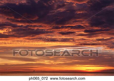 Sunset at sea, dark clouds in orange streaked sky View Large Photo Image Stock Image - Sunset at sea, dark clouds in orange streaked sky . Fotosearch