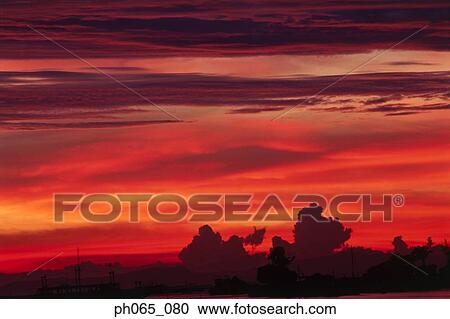 Sunset at sea, dark clouds in orange streaked sky View Large Photo Image Stock Image - Sunset at sea, dark clouds in orange streaked sky . Fotosearch