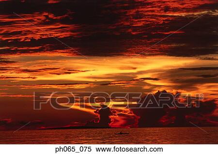 Sunset at sea, dark clouds in orange streaked sky View Large Photo Image Stock Photography - Sunset at sea, dark clouds in orange streaked sky . Fotosearch