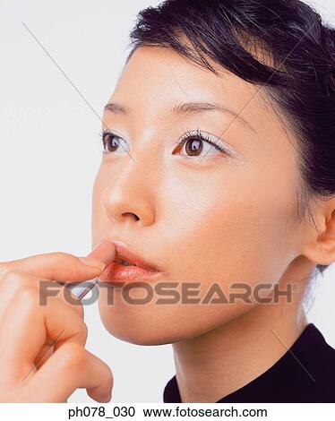 Young woman applying lipstick View Large Photo Image Stock Image - Young woman applying lipstick. Fotosearch