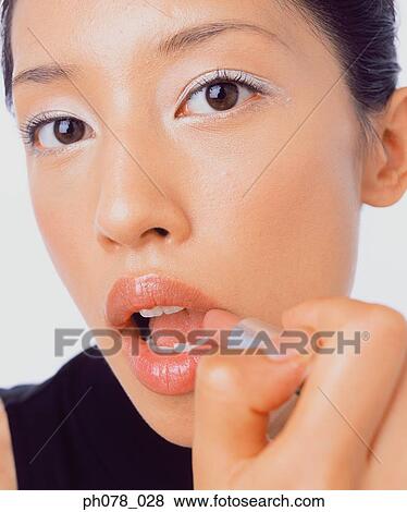 Young woman applying lipstick View Large Photo Image Stock Photo - Young woman applying lipstick. Fotosearch