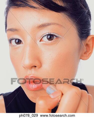 Young woman applying lipstick View Large Photo Image Stock Photo - Young woman applying lipstick. Fotosearch